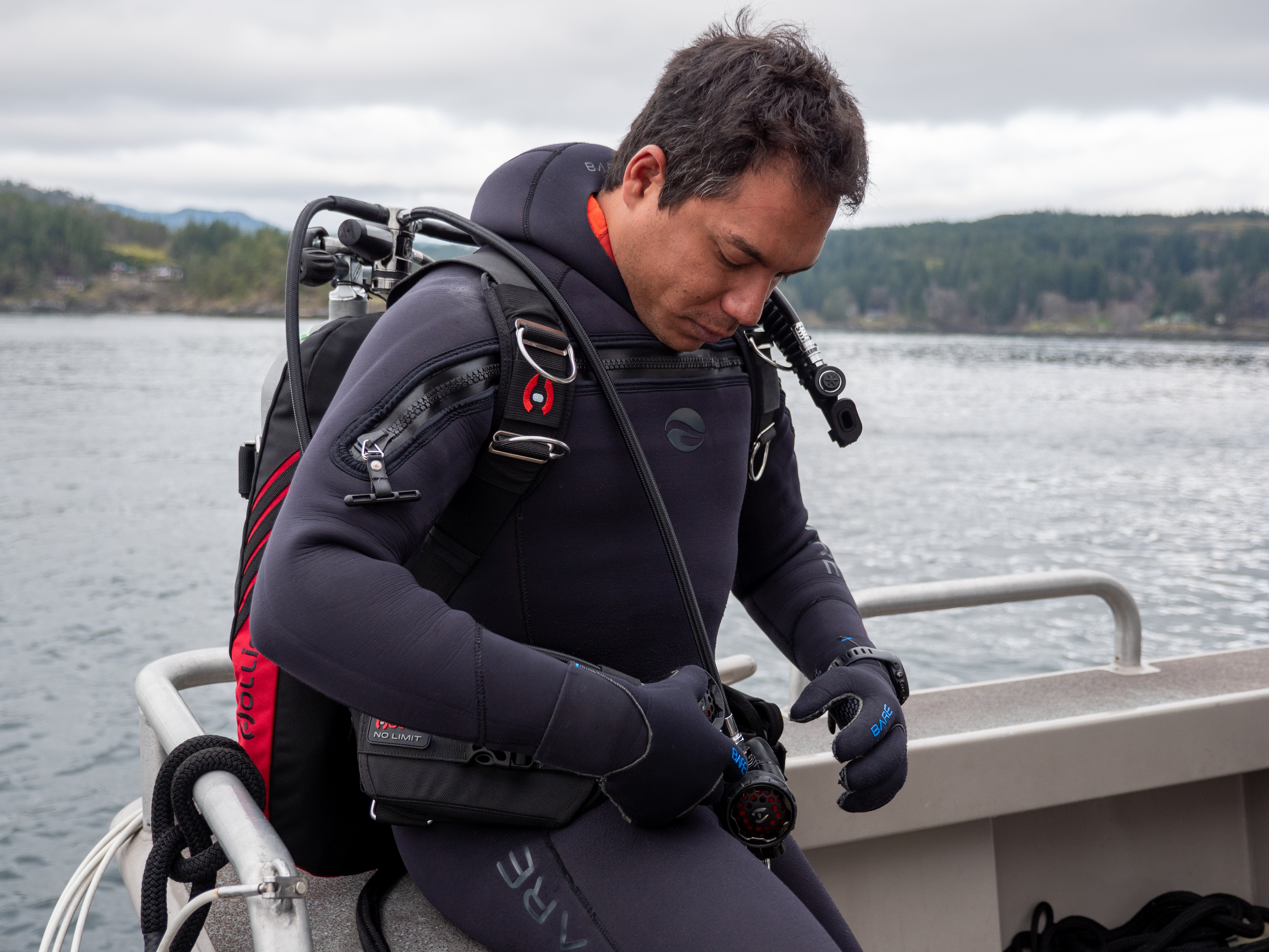 man wearing a Hollis backmount sitting on the edge of a boat before starting his dive
